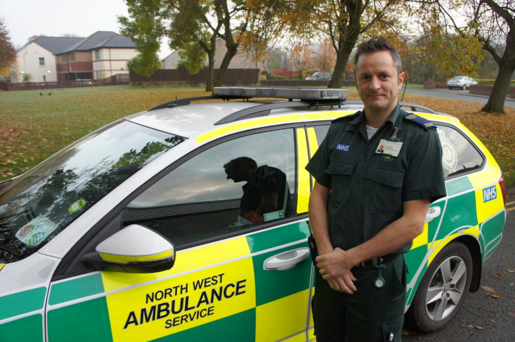 Man stood next to ambulance.