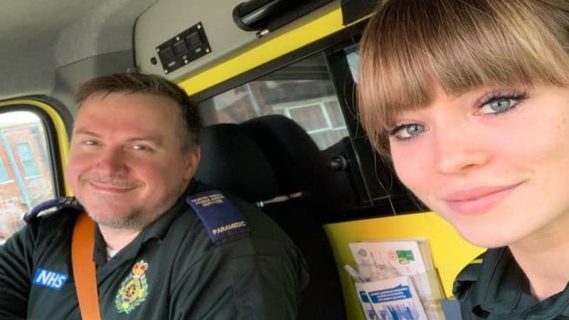 Two smiling staff members sat in an ambulance