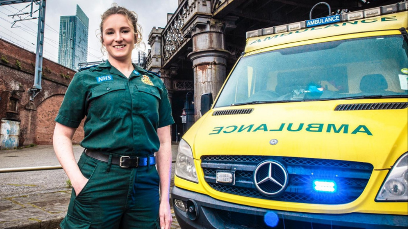 Paramedic Claire in uniform stood next to a rapid reponse ambulance.