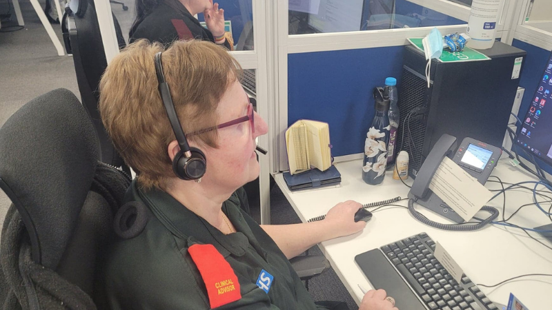 Clinical advisor wearing a headset sat in front of a computer