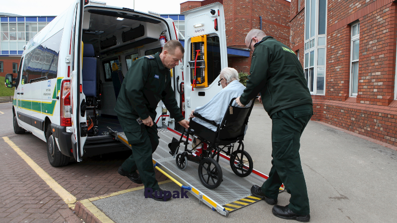 Patient transport service ambulance crew pushing a patient onto the back of an ambulance. 