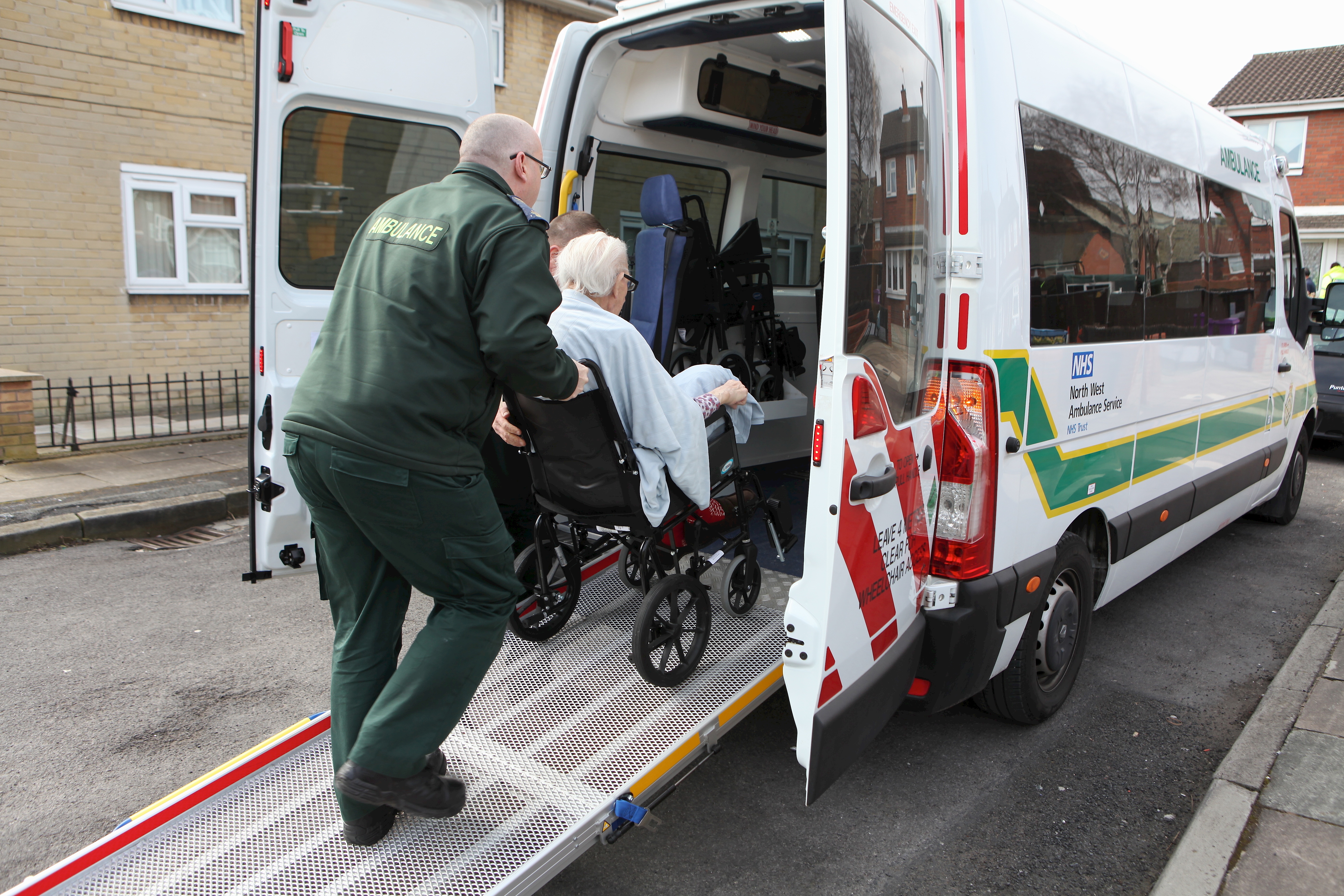 person in wheelchair being pushed into an ambulance.