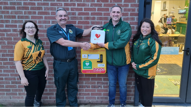 group of people standing in front of newly installed defibrillator 