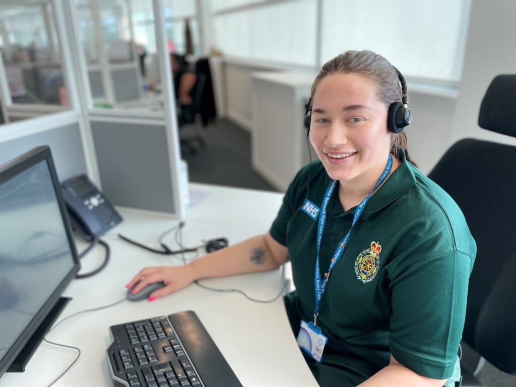 an nwas call handler sitting at a computer with a headset on