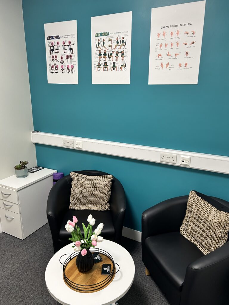 111 wellbeing room, with chairs, a table with flowers on, and posters on the wall.