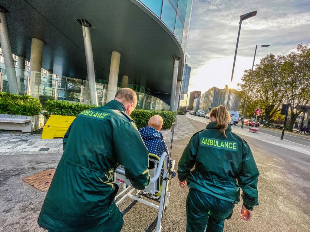 pts crew wheeling patient in a wheelchair into a hospital