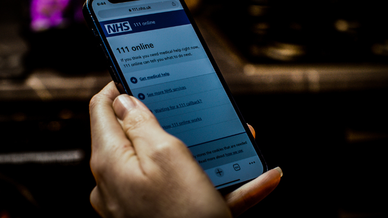 A mobile phone displaying the NHS 111 website