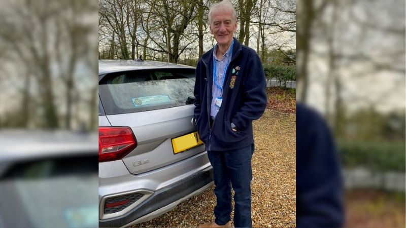 Volunteer Car Driver Mike standing next to his silver car.