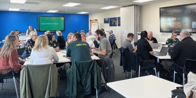 Ambulance staff around breakout tables at a training session.