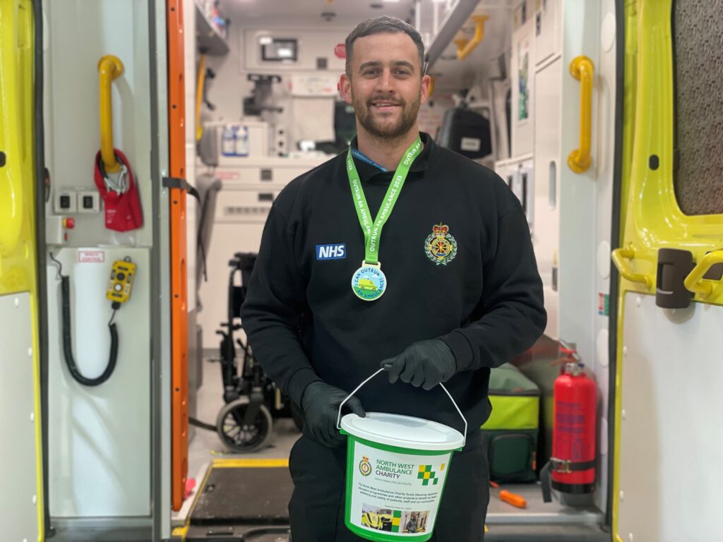 ambulance staff member holding a charity bucket in front of an ambulance