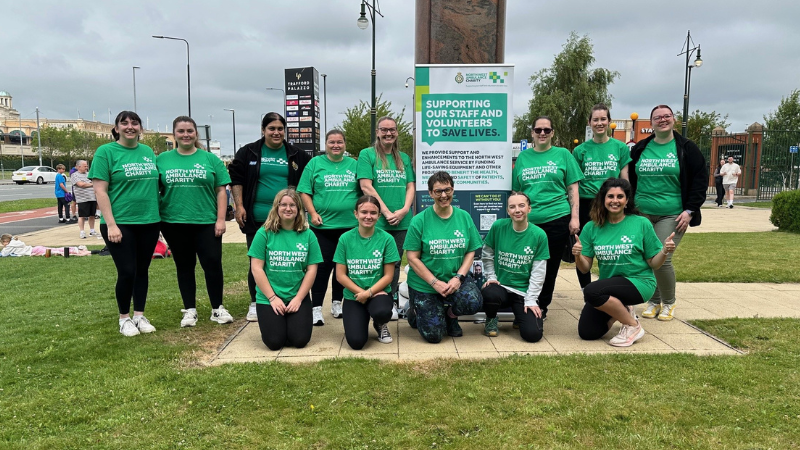 Group of people standing on grass wearing green North West Ambulance Charity t-shirts