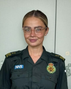 Young woman wearing glasses and green ambulance uniform