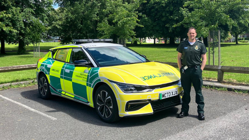 A man in green uniform stood to the side of an RRV. It is a sunny day.