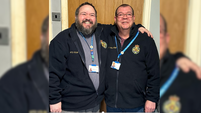 Siblings and volunteer car drivers Jay and Lee arm in arm smiling.