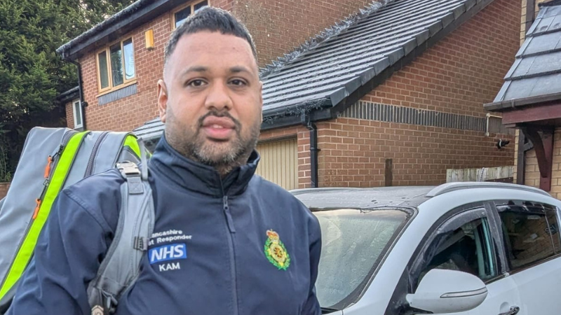 A community first responder carrying his kit bag standing in front of a residential building.