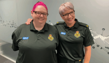 Cath (right) and Jackie in uniform side by side smiling and standing in front of a glass wall.