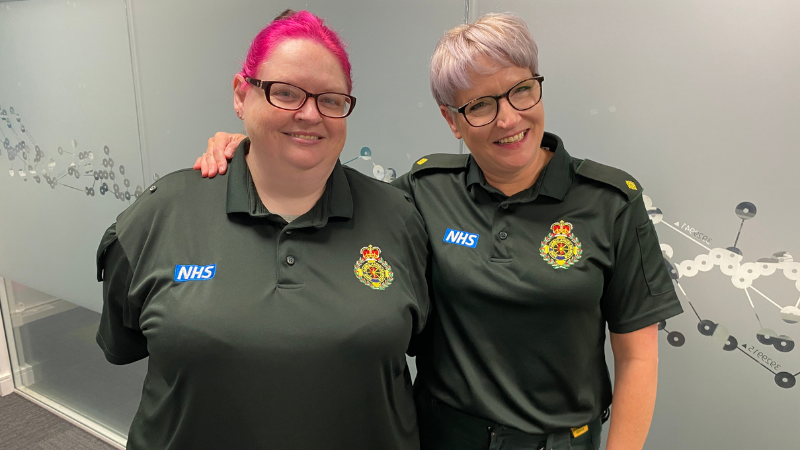 Cath (right) and Jackie in uniform side by side smiling and standing in front of a glass wall.