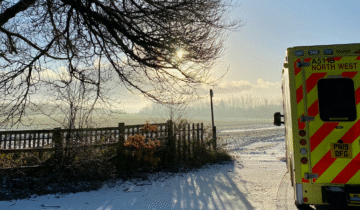 Ambulance parked on a road with frost on the ground.