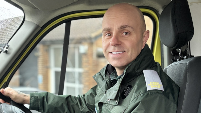 Brian smiling at the camera sat in the cab of an ambulance.