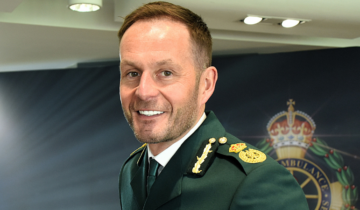 Head and shoulders image of Dan in his dark green dress ambulance uniform, smiling at the camera.