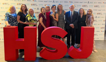 The MAMAS Team stand infront of large red HSJ letters at an awards ceremony.