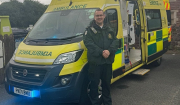 a man in green uniform stood in front of an ambulance.