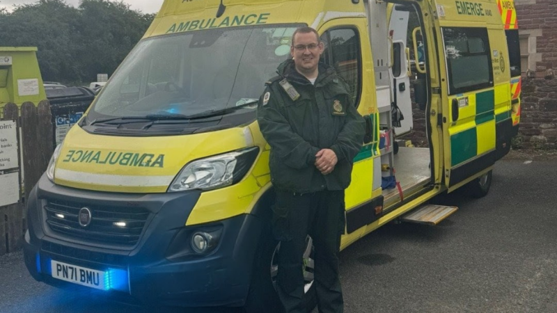 a man in green uniform stood in front of an ambulance.