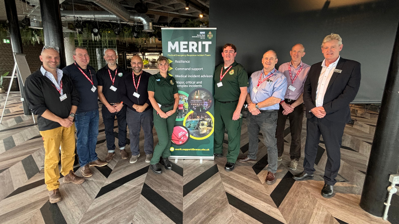 A group of emeregncy reponse staff stand togther for a picture next to a MERIT team banner.