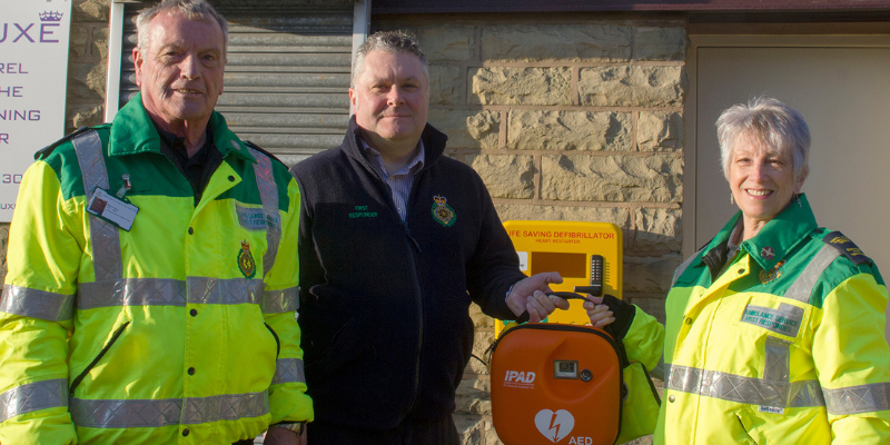 Rossendale community group celebrates huge milestone and smile to camera with defibrillator.
