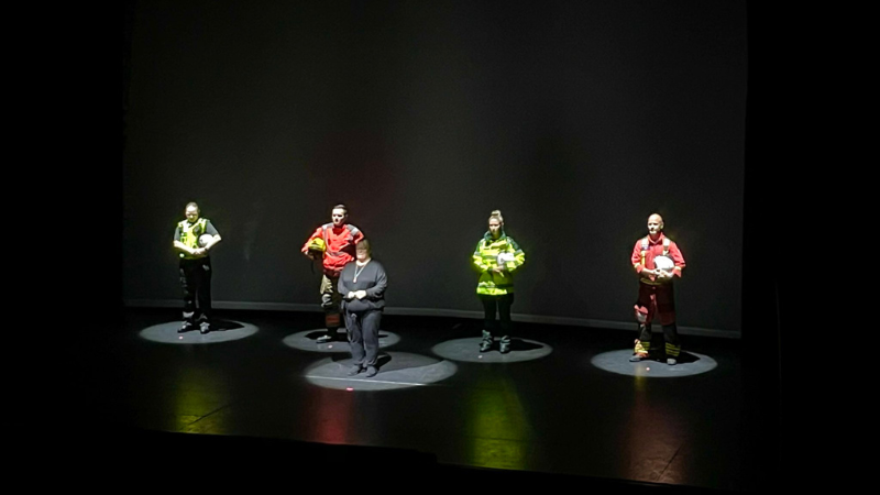 Group of emergency service staff stood on a stage with spotlights