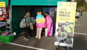 A green gazebo with three people in it with a pop up stand to the left which says: 'Hello we are NWAS'
