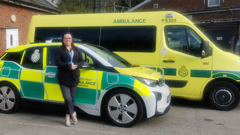 Vicki Batley standing in front of a response vehicle and ambulance