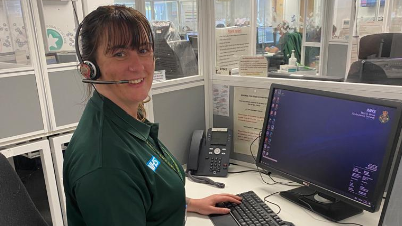Emergency Call handler Karen smiling with headset sat at desk.